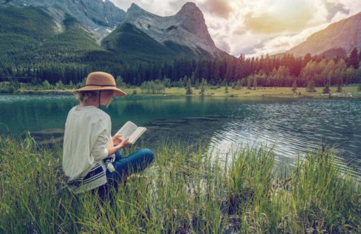 Ragazza legge un libro tra le montagne