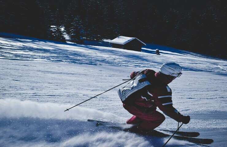 Sciatore con bastoncini da sci scende lungo la pista da sci